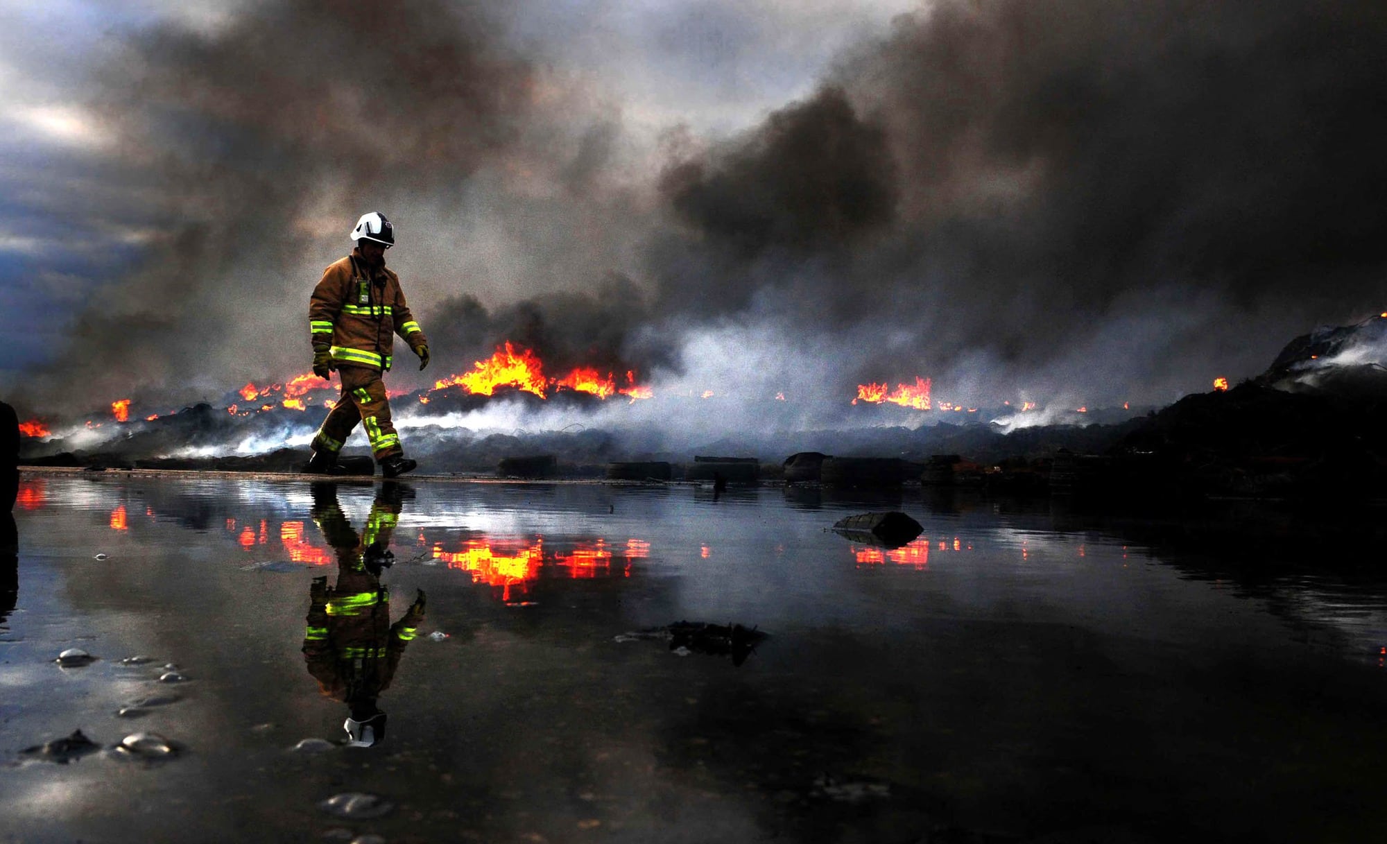 Anthony Chappel-Ross/ Yorkshire Post. Fireman walk past Elmet Tyre Fire at Sherburn in. Finalist in the Genesis Imaging Regional Photographer of the Year category at the 2015 Picture Editors Guild Awards.